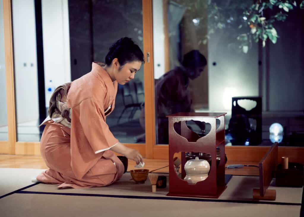 Mujer con kimono iromuji realizando la ceremonia del té