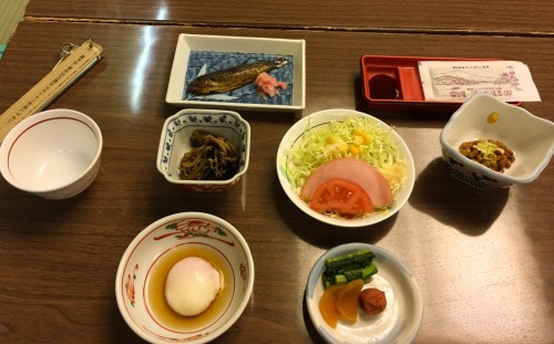 Natto, baked fish, miso soup, salad, soft-boiled egg, rice, and boiled vegetables