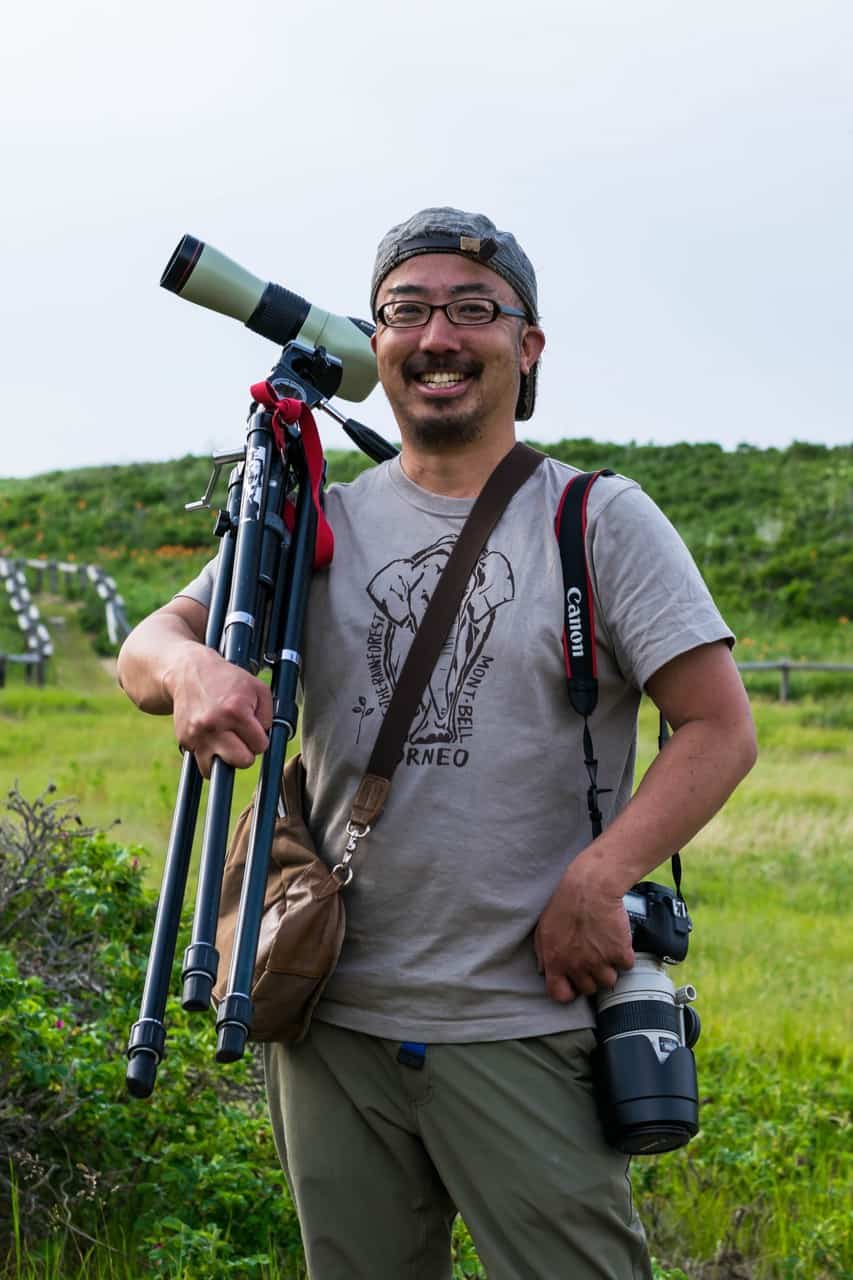 Man with two cameras and a tripod posing for the camera