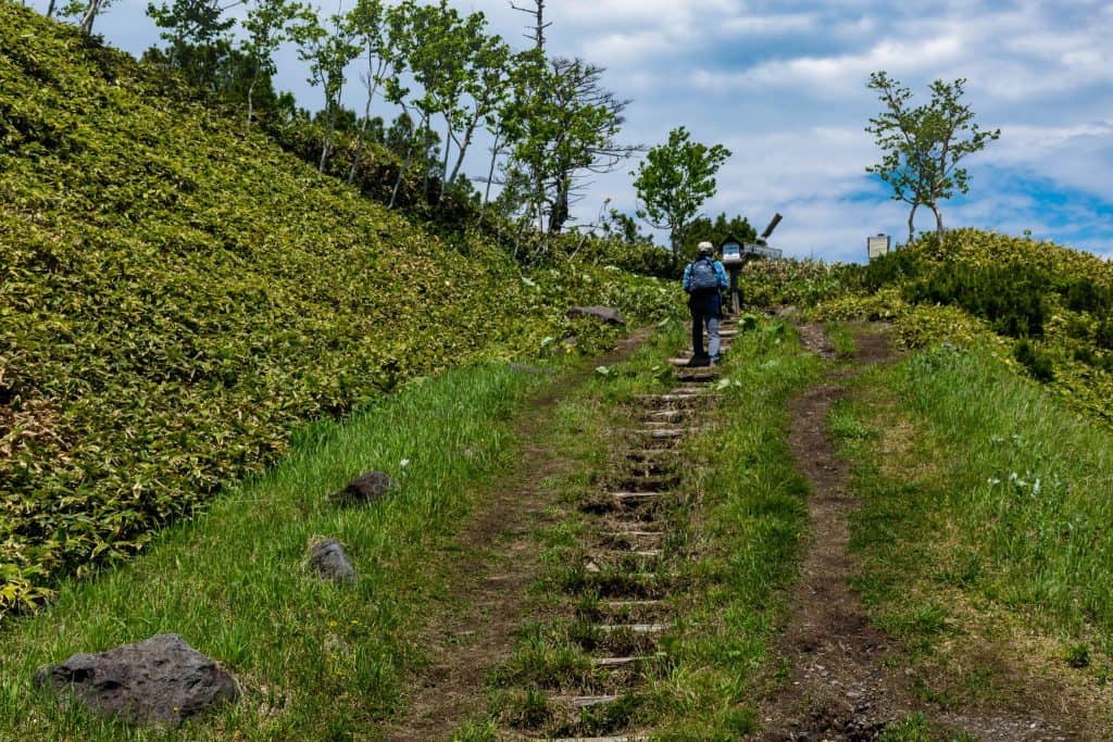 man trekking up a mountain in hokkaido, japan