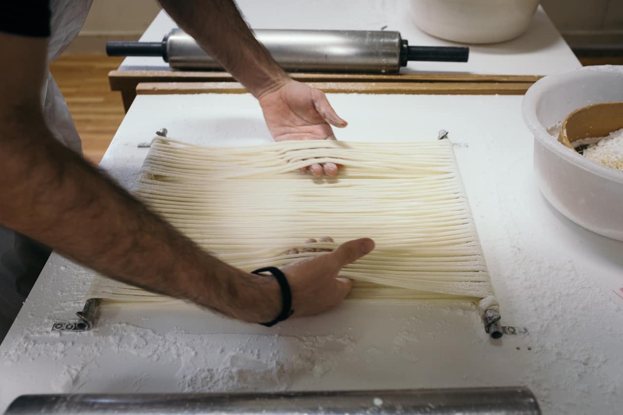a man's hands preparing udon noodles in japan