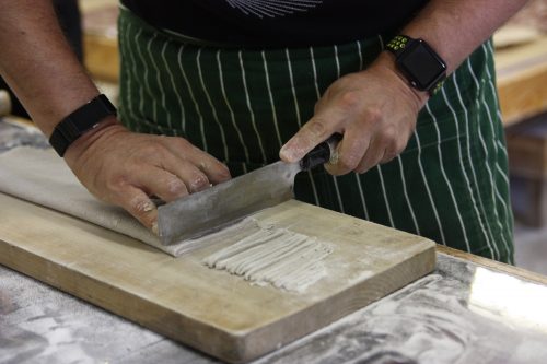 Thinly slicing dough to make homemade soba noodles.