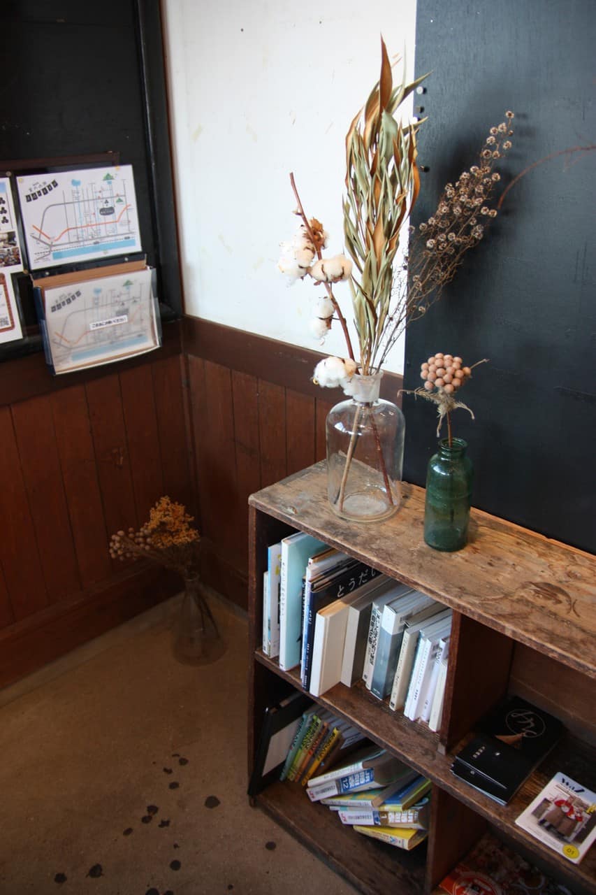 A small bookshelf at the restaurant with books, magazines and decorations.