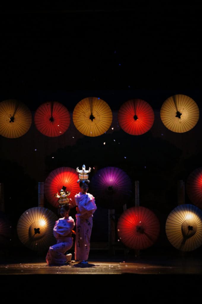 The two dancers standing in the dark, their lanterns glowing