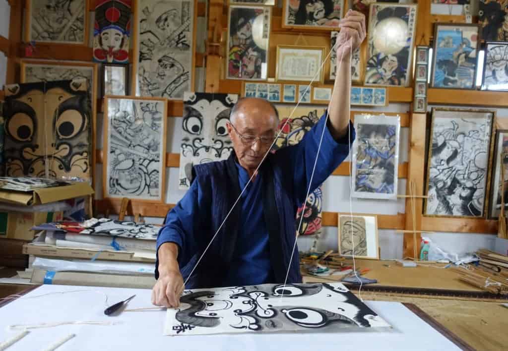 The craftsman hangs the strings that will allow the traditional kite to fly
