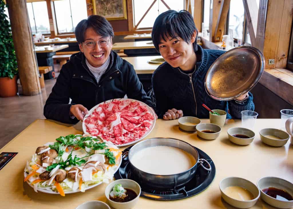 two people in front of shabu shabu platter in japan