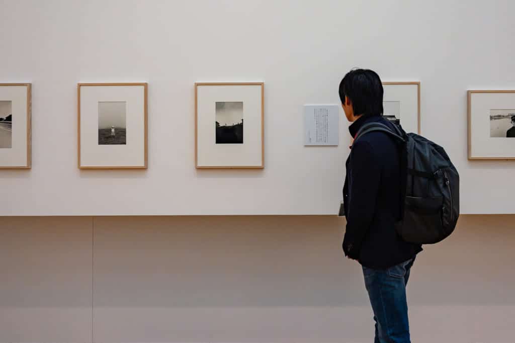 Man standing in front of a series of framed photographs in the Shoji Ueda Museum of Photography