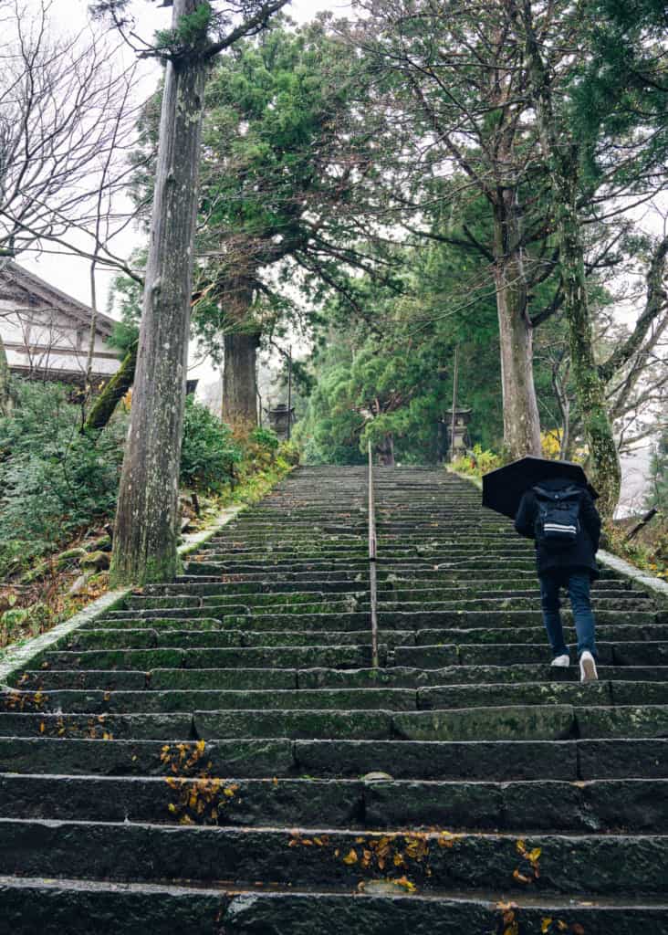 Man walking up stone stairs with umbrella in Japan