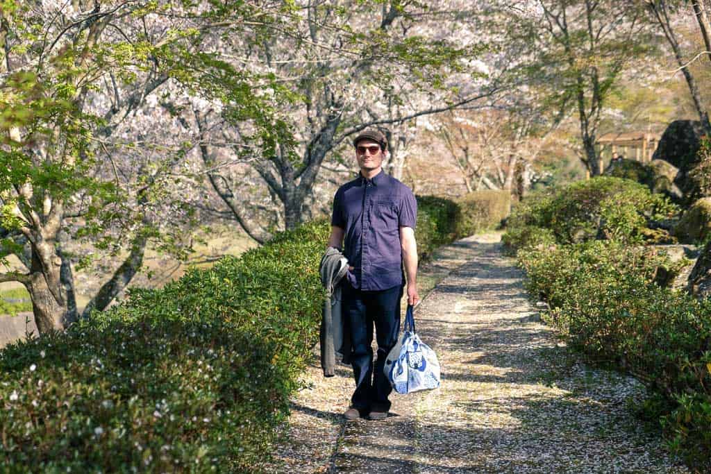 man standing in traditional japanese park during sakura cherry blossom season in japan