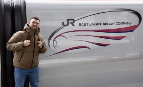 Standing in front of the Shinkansen with logo