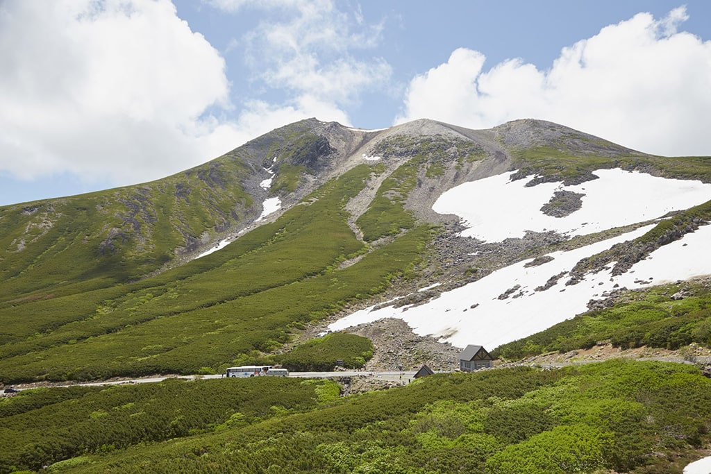 Some snow remaining on the top of a green mountain in Nagano