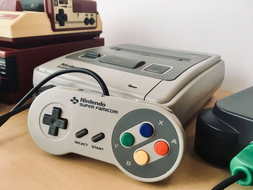 The Super Famicom, the Japanese equivalent of the Super Nintendo Entertainment System, between a Famicom atop a Famicom Disk System (left) and a Nintendo 64 (right)