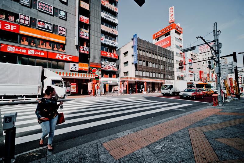 Girl crossing road with KFC in the background in Tokyo