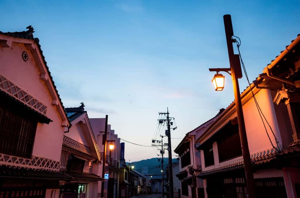 Street lined with Japanese traditional white-walled houses at dusk in Joge