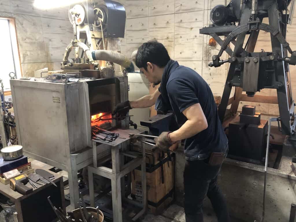 A Japanese blacksmith working to forge knifes.