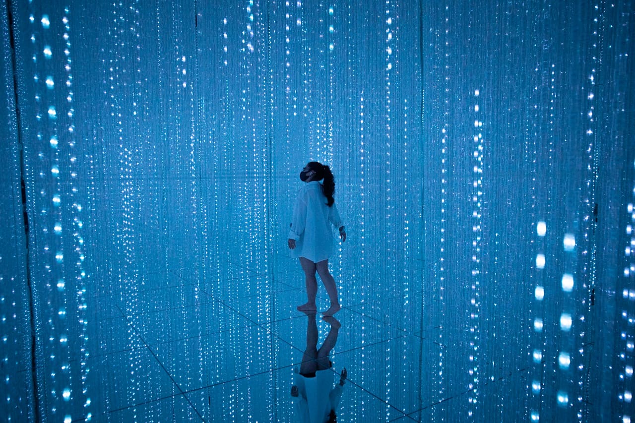 woman wandering around blue light crystals at teamLab Planets in Tokyo