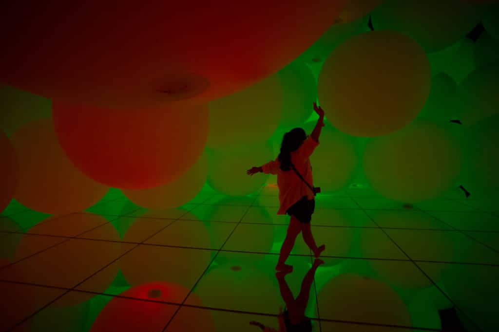 woman enjoying surrounded by spheres of light at teamLab Planets in Tokyo