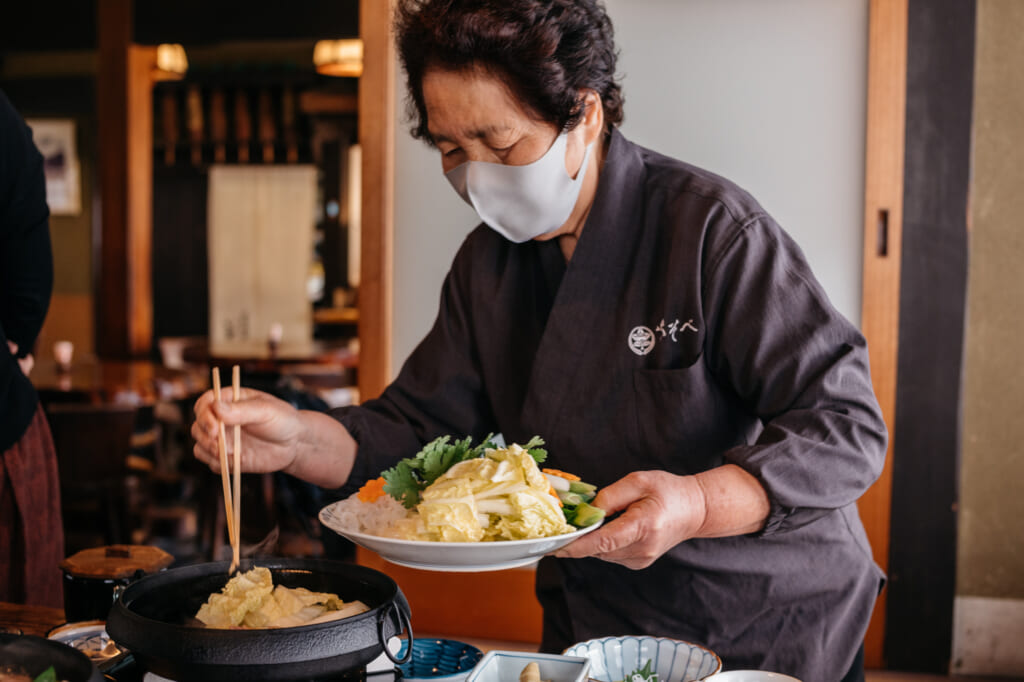 being served traditional Japanese sukiyaki meal 