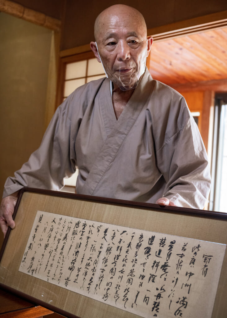 Buddhist Priest holds Japanese letter written in kanji in usuki, Oita, Kyushu