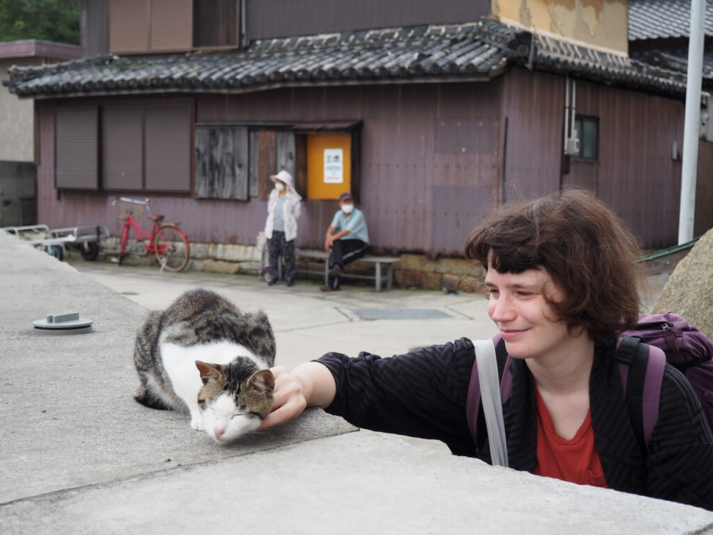 Clementina stroking a cat on Manabeshima, a cat Island in Japan