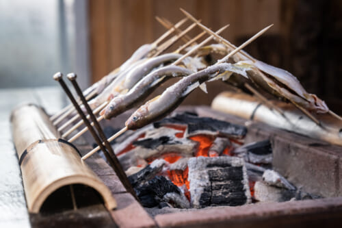 Skewered fish grilling over charcoal