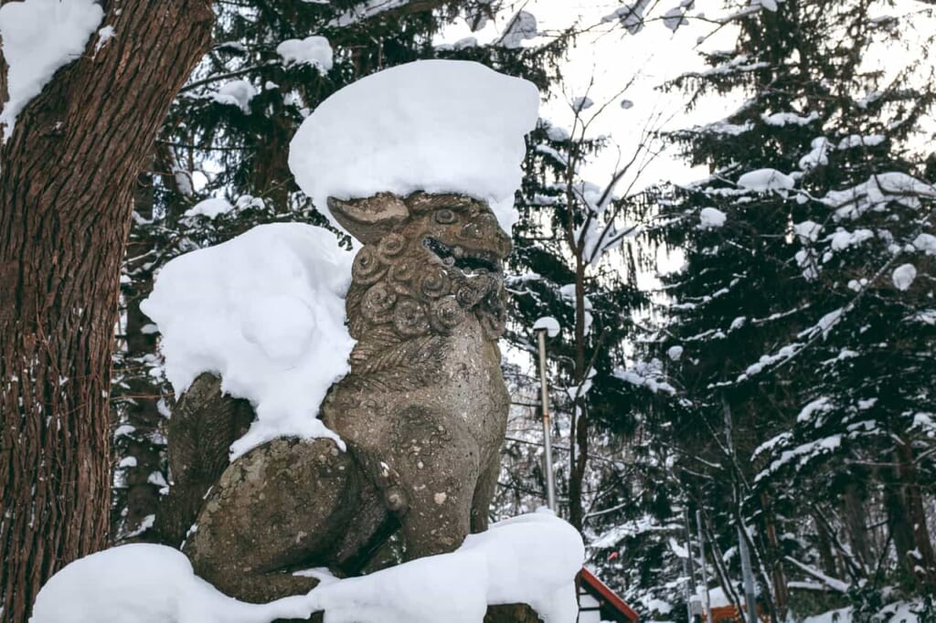 lion-dog statue covered in snow guards gates at Japanese Shrines and Temples