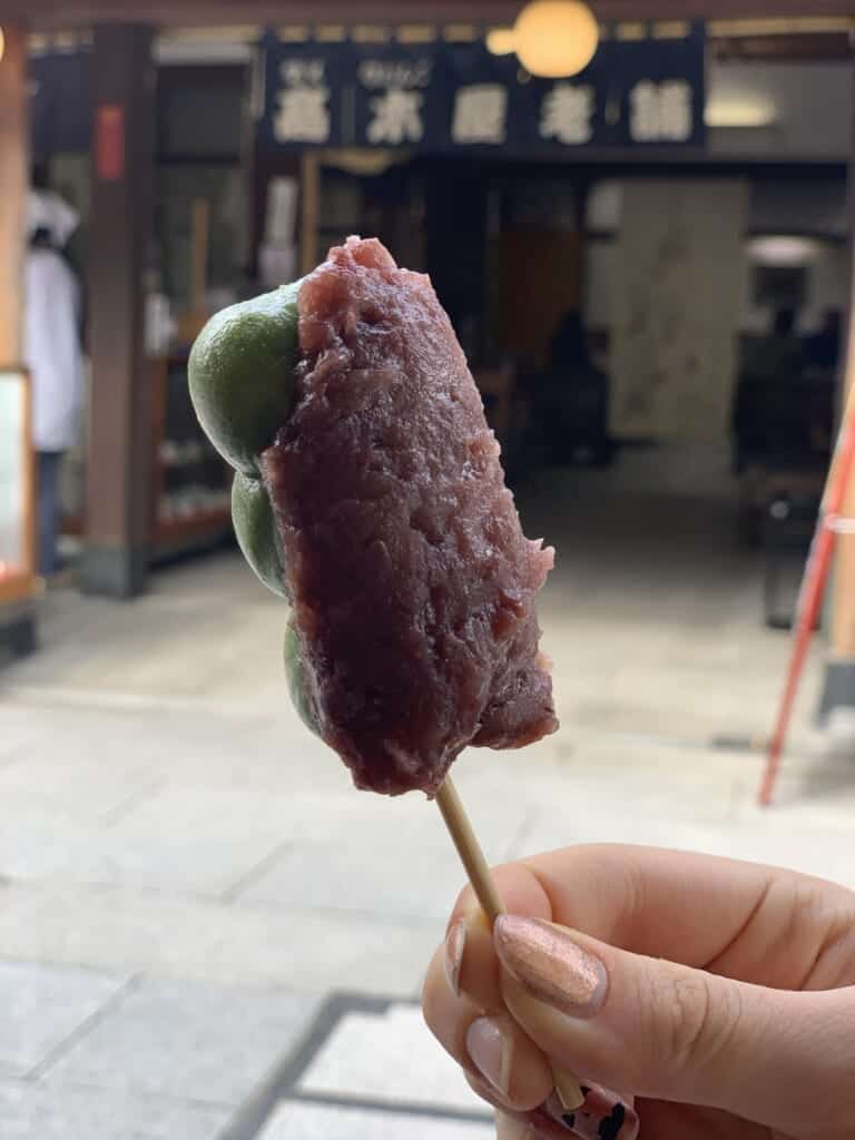 A delicious stick of kusa dango, a stick of green rice balls topped with a thick red-bean paste.