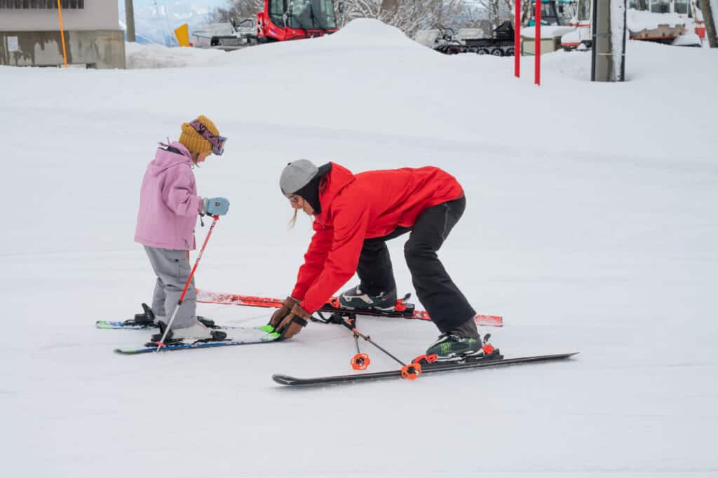 instructor helps child learn to ski at madarao mountain resort in nagano