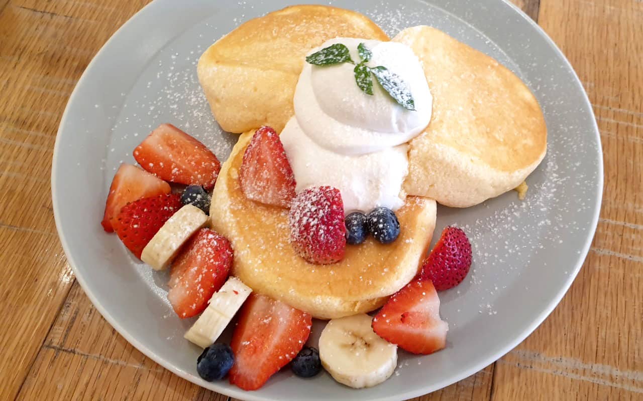 Fluffy pancakes with fruits and whipped cream