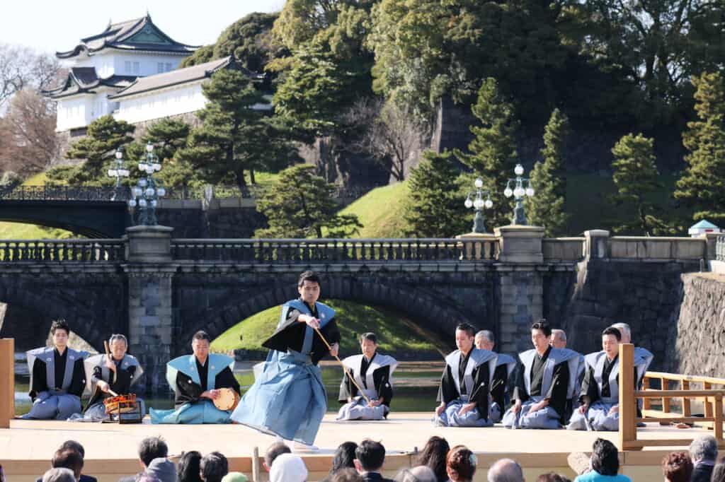 Noh dancer on stage in front of bridge and palace