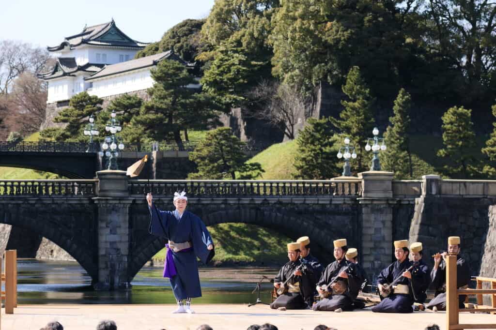 Male dancer holding flag on stage in front of bridge and palace