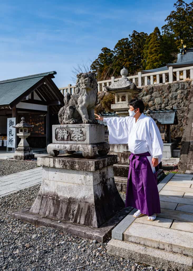 Japanese shrine priest with guardian statue at akihasan jinja near tokyo, Japan