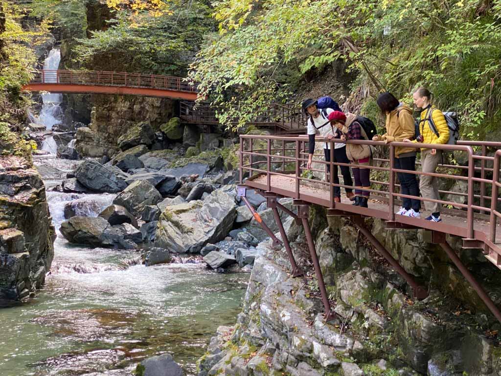 people look out over a river near a waterfall while hiking in Japan