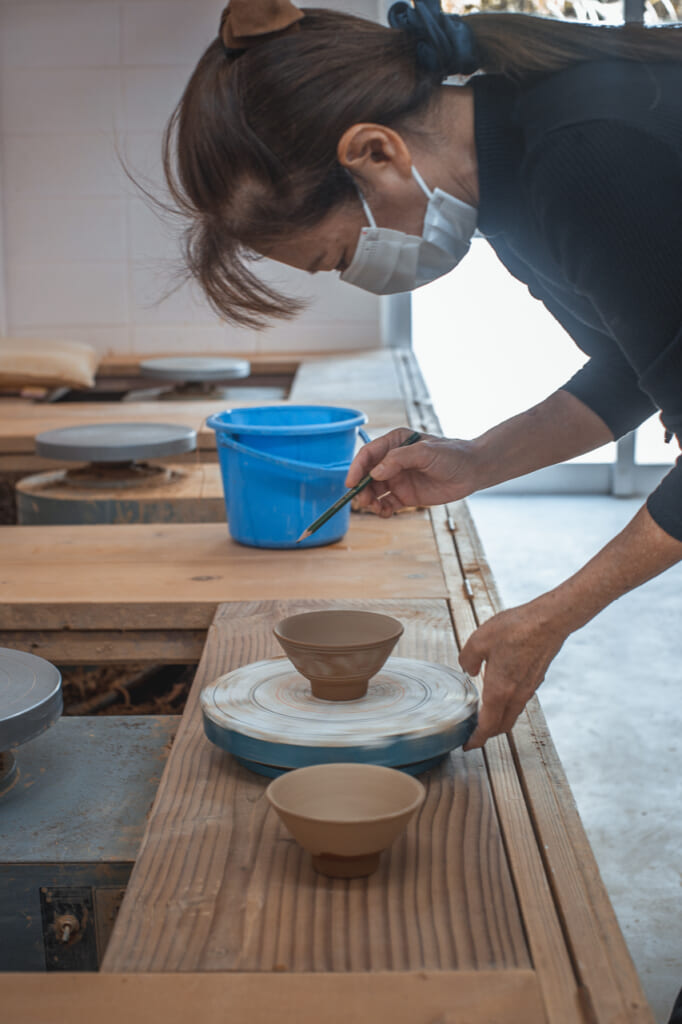 a woman painting a ceramic bowl in Okinawa, Japan