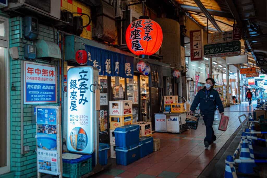 person walking in an alleyway in tenjinbashisuji shopping street in japan