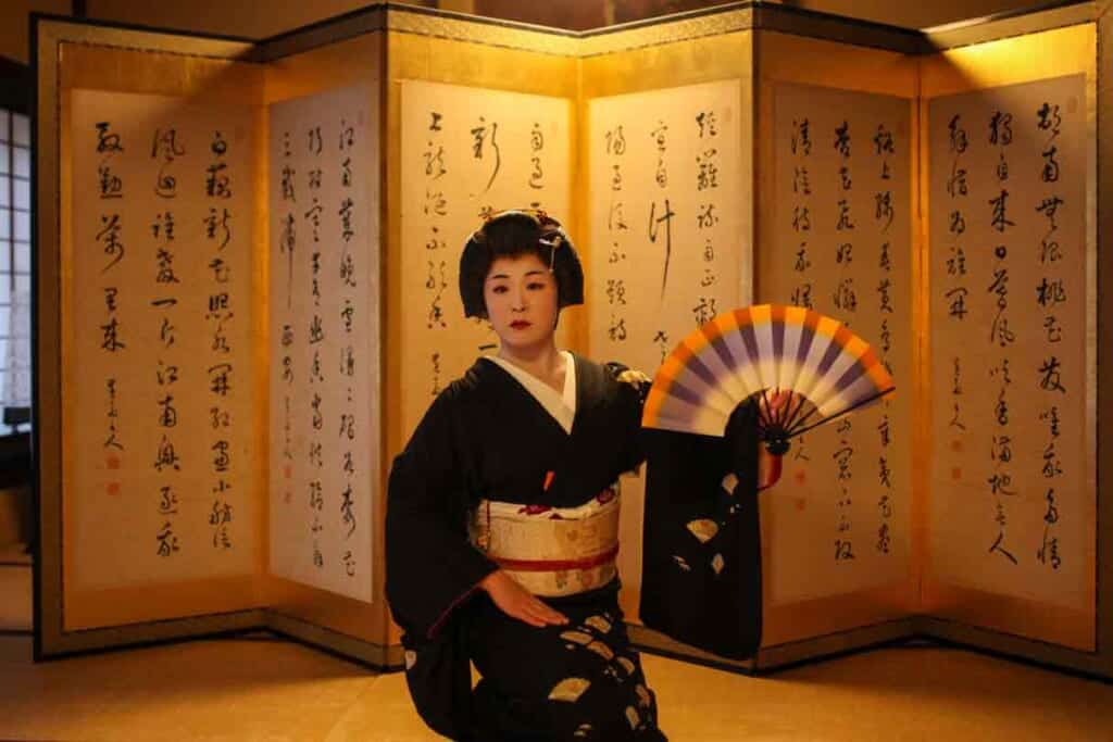 Geisha sitting with a fan in Japan