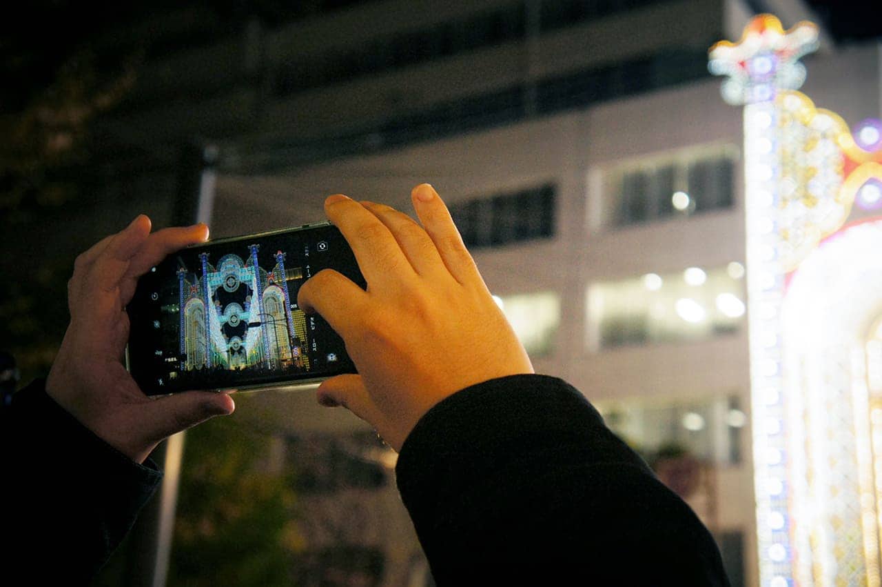 hands photographing Kobe Luminarie with a smartphone