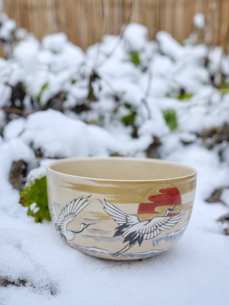 A Japanese Tea bowl decorated with cranes in the snow.