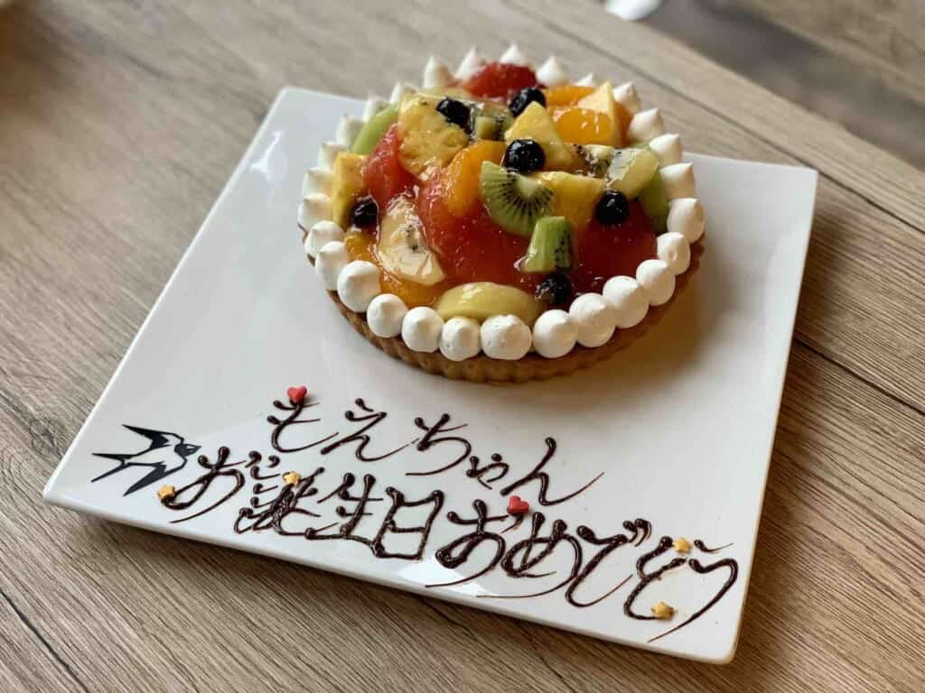 Japanese fruit cake with "Happy Birthday" written in Japanese on plate