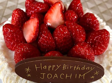 A strawberry shortcake with a "Happy Birthday" sign on chocolate in front 