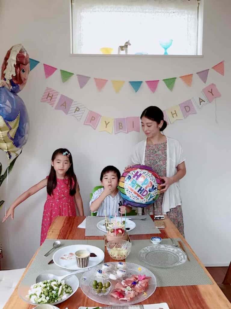 kids and a mother celebrating a birthday with cake and candles in Japan