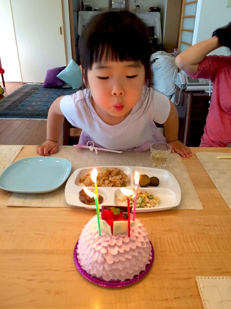 little girl blowing out candles on her birthday cake in Japan