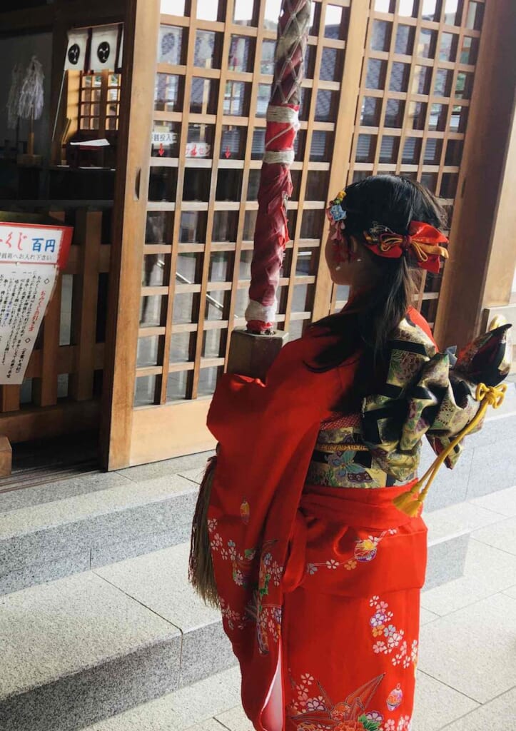little girl in traditional japanese kimono praying at a Shinto Shrine