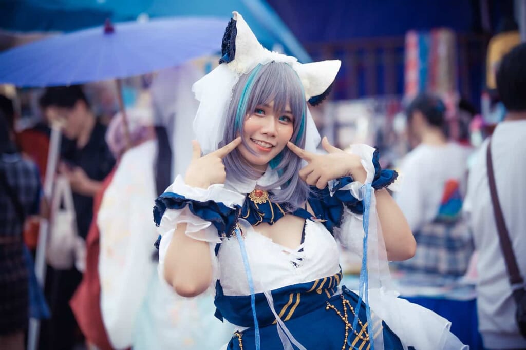 Girl wearing cosplay anime outfit and giant cat ears and posing with fingers on cheek