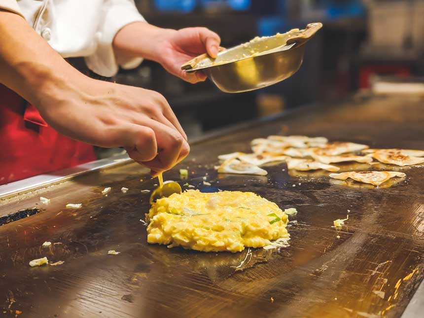 hands making okonomiyaki dish in Japan 