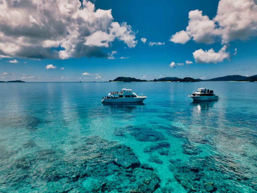 diving tour boats in shallow blue waters filled with coral reefs in Kerama islands, Okinawa