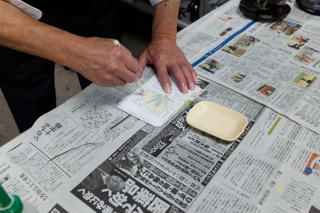 A craftsman demonstrating maki-e lacquerware printing technique