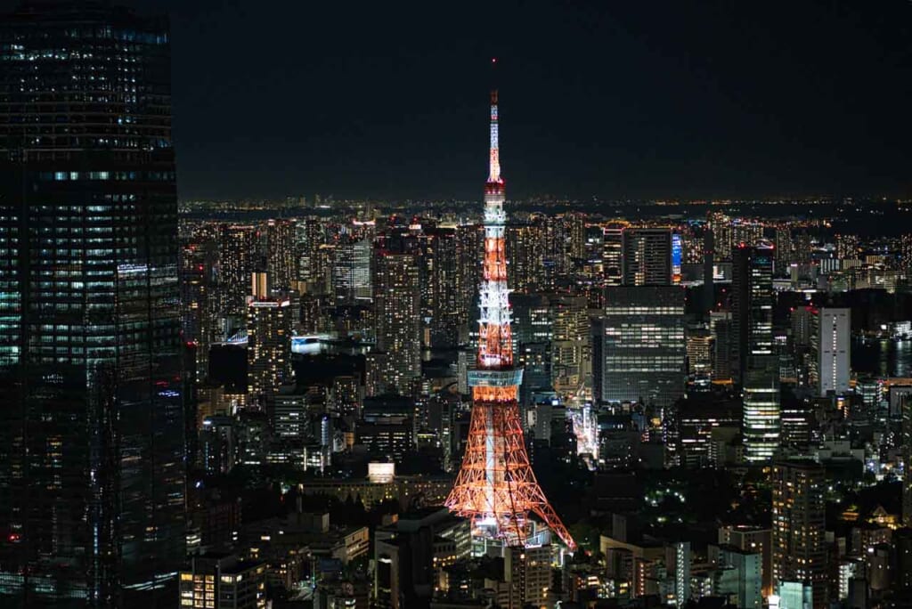 night time view of tokyo tower lit up in expansive cityscape