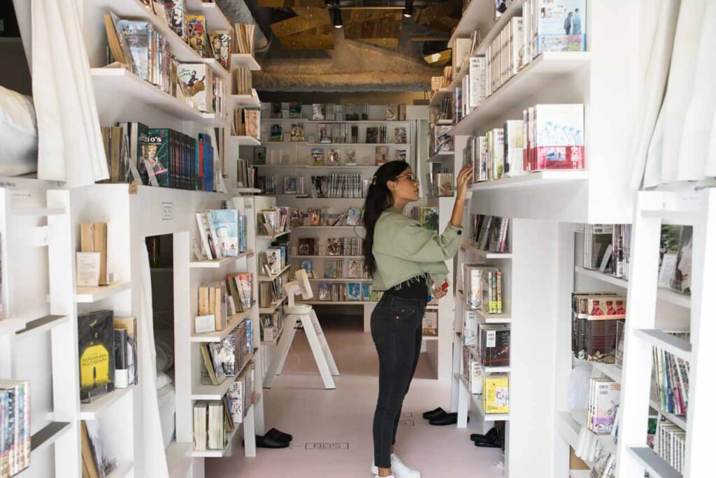 manga hotel in tokyo with woman browseing through a manga collection in a capsule style hotel in Japan