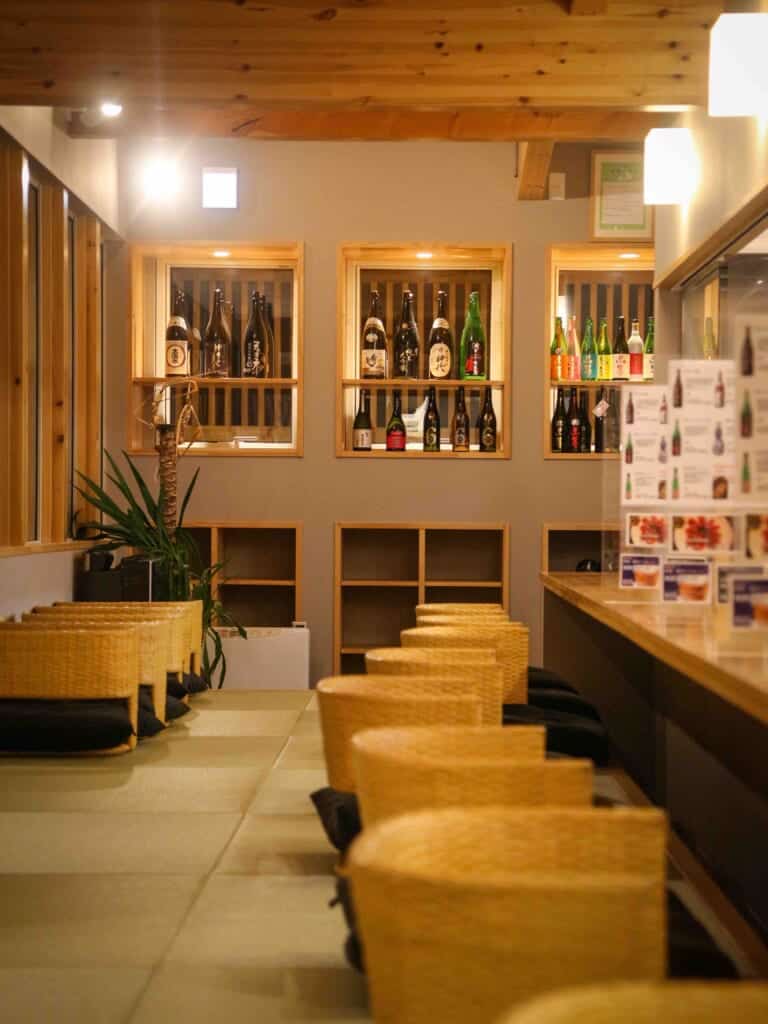 a row of bar chairs and sake bottles